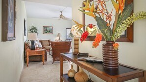 A living room with wicker furniture, a wooden coffee table, and a vase with flowers.