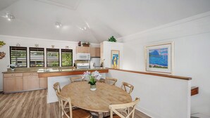 Una cocina moderna con armarios de madera, una isla central y un comedor con una mesa redonda y sillas.