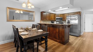 Una cucina moderna con mobili in legno, un frigorifero in acciaio inossidabile e un'area pranzo con tavolo e sedie in legno.