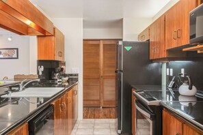 Uma cozinha moderna com armários de madeira, uma geladeira preta e uma cafeteira.