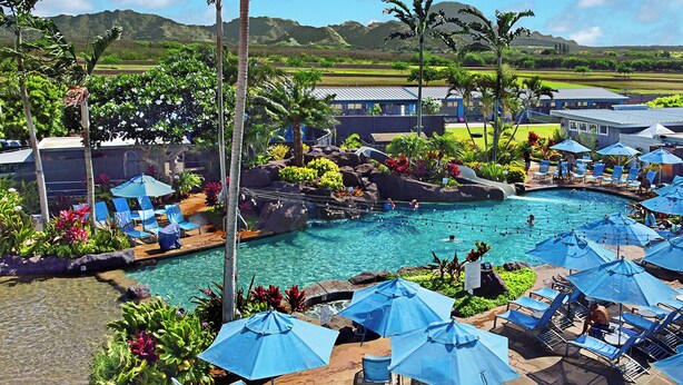 A resort with a swimming pool, lounge chairs, and umbrellas.