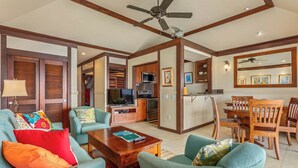 A spacious living area with a sofa set, a coffee table, and a dining table with chairs. There is a kitchen area with a microwave and a refrigerator.