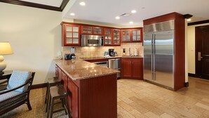 Une cuisine moderne avec des meubles en bois, un réfrigérateur en acier inoxydable et un plan de travail en granit.