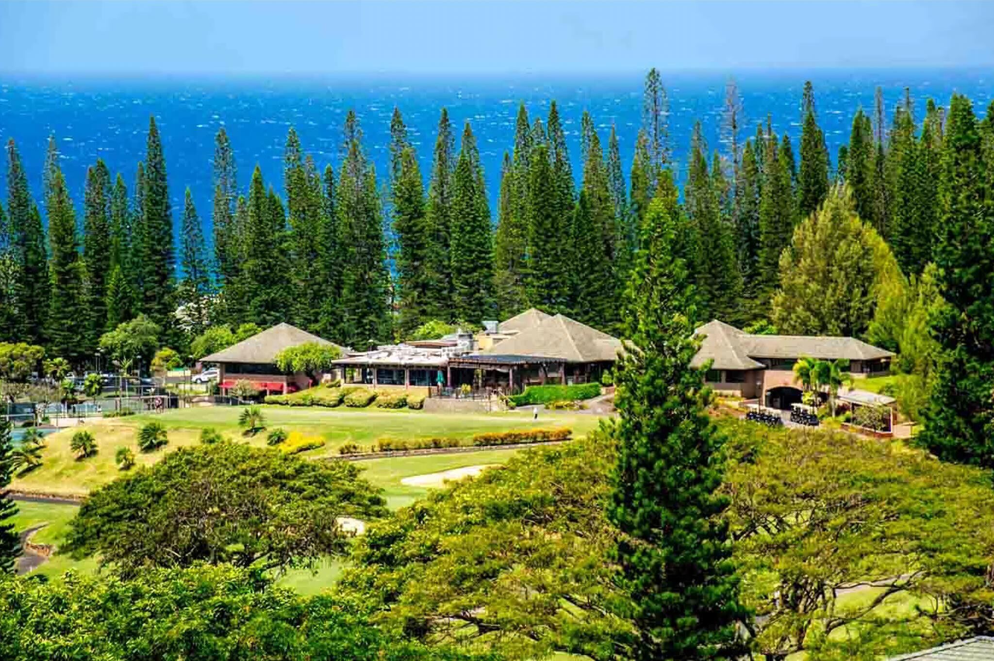 Un resort con varias edificaciones, un campo de golf y vista al océano.