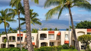 A resort with multiple-story buildings, palm trees, and a view of the ocean and mountains. - Palms at Wailea Villa 806 Ocean View 2BD 2BA (Wailea)