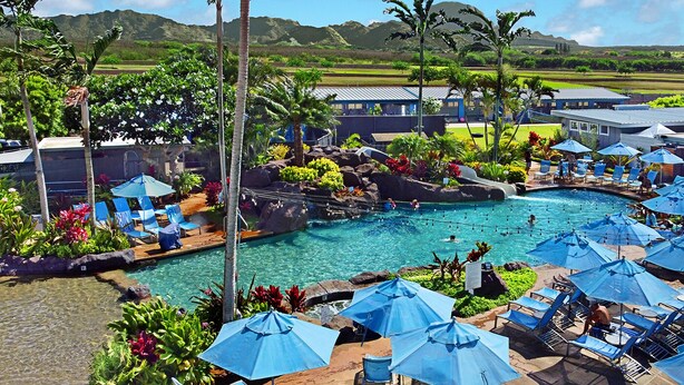 A resort with a swimming pool, lounge chairs, and umbrellas.