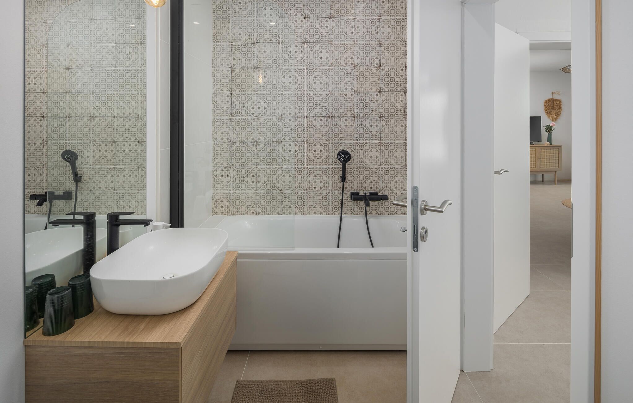 A modern bathroom with a freestanding bathtub, a large mirror, and a wooden vanity.