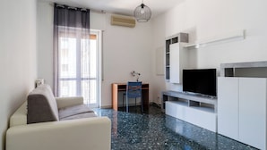 A modern living room with a sofa, a TV, and a desk with a chair. - Appartamento Onda Blu by Wonderful Italy (Bari)