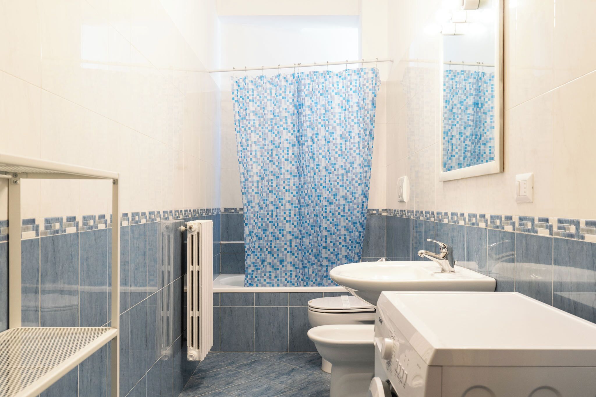 A bathroom with a bathtub, toilet, and sink, featuring blue and white tiles.
