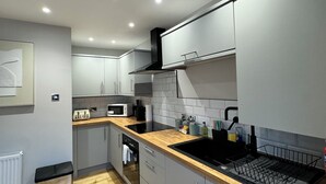 Una cocina moderna con armarios grises, un lavamanos negro y encimeras de madera.