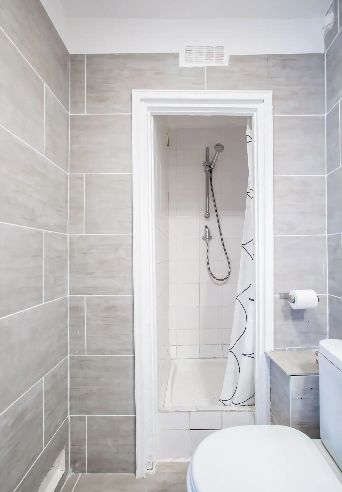 A bathroom with a shower, toilet, and a small sink.