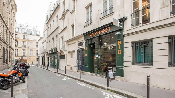 A street with a building labeled "HOLY PLANET BIO" and a bicycle lane. - Well-appointed St. Michel studio (Paris)