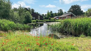 Eine friedliche Flusslandschaft mit einem Holzhaus, einer kleinen Brücke und üppigem Grün.