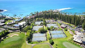 Vista aérea de un complejo turístico costero con canchas de tenis, un campo de golf y una playa.