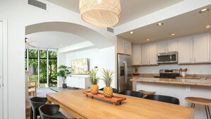 Una cocina moderna con armarios blancos, electrodomésticos de acero inoxidable y una mesa de comedor de madera con sillas.