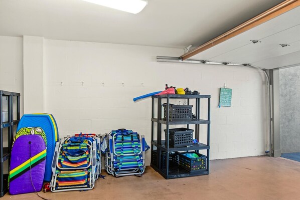 A garage with a white wall, a metal shelf unit, and a surfboard.