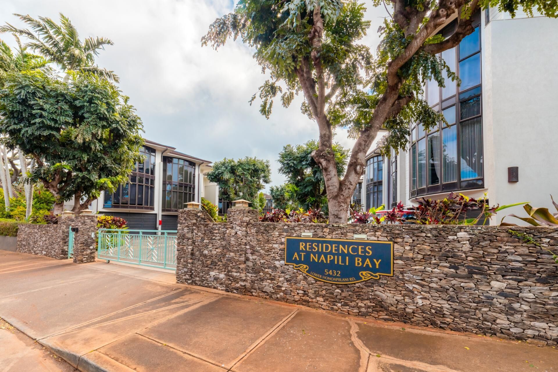 Zona residencial con un muro de piedra y un cartel que dice "Residences at Napili Bay Lower Honoapiwani Rd.".