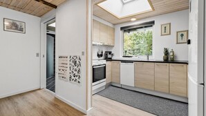 A modern kitchen with wooden cabinets, a skylight, and a view of greenery outside. - 2 bedroom nice home in Rønde (Rønde)