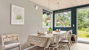 A dining area with a table set for four, surrounded by chairs, a pendant light, and a view of greenery outside. - 2 bedroom nice home in Rønde (Rønde)