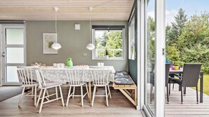 A dining area with a table and chairs, a bench, and a view of greenery outside. - 2 bedroom nice home in Rønde (Rønde)