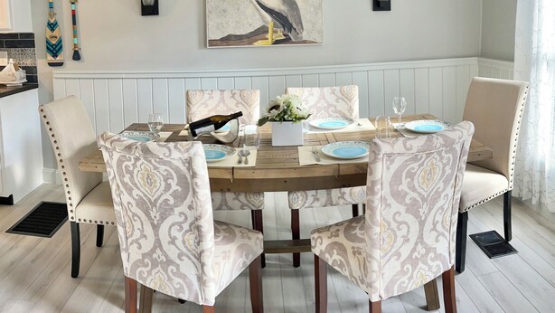 Un comedor con una mesa de madera dispuesta para cuatro personas, rodeada de sillas con estampado.