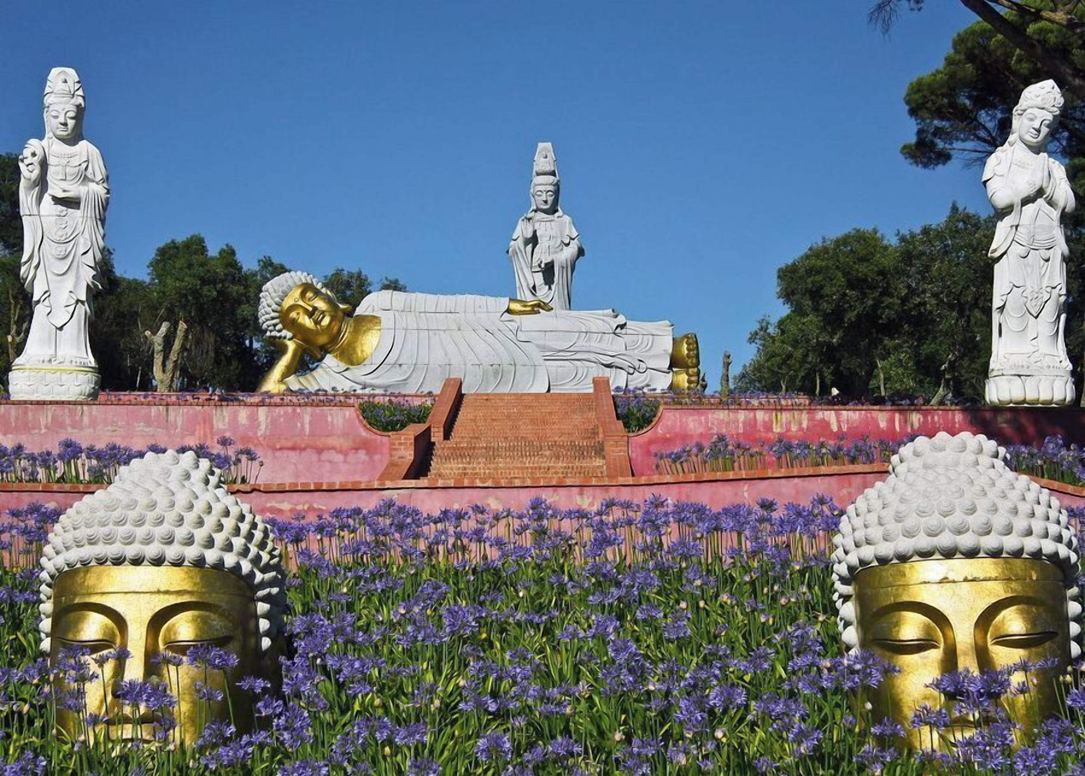 A large Buddha statue lying down with other statues around it.