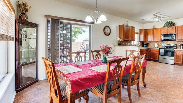 Un'area pranzo con tovaglia rossa, sedie di legno e un lampadario.