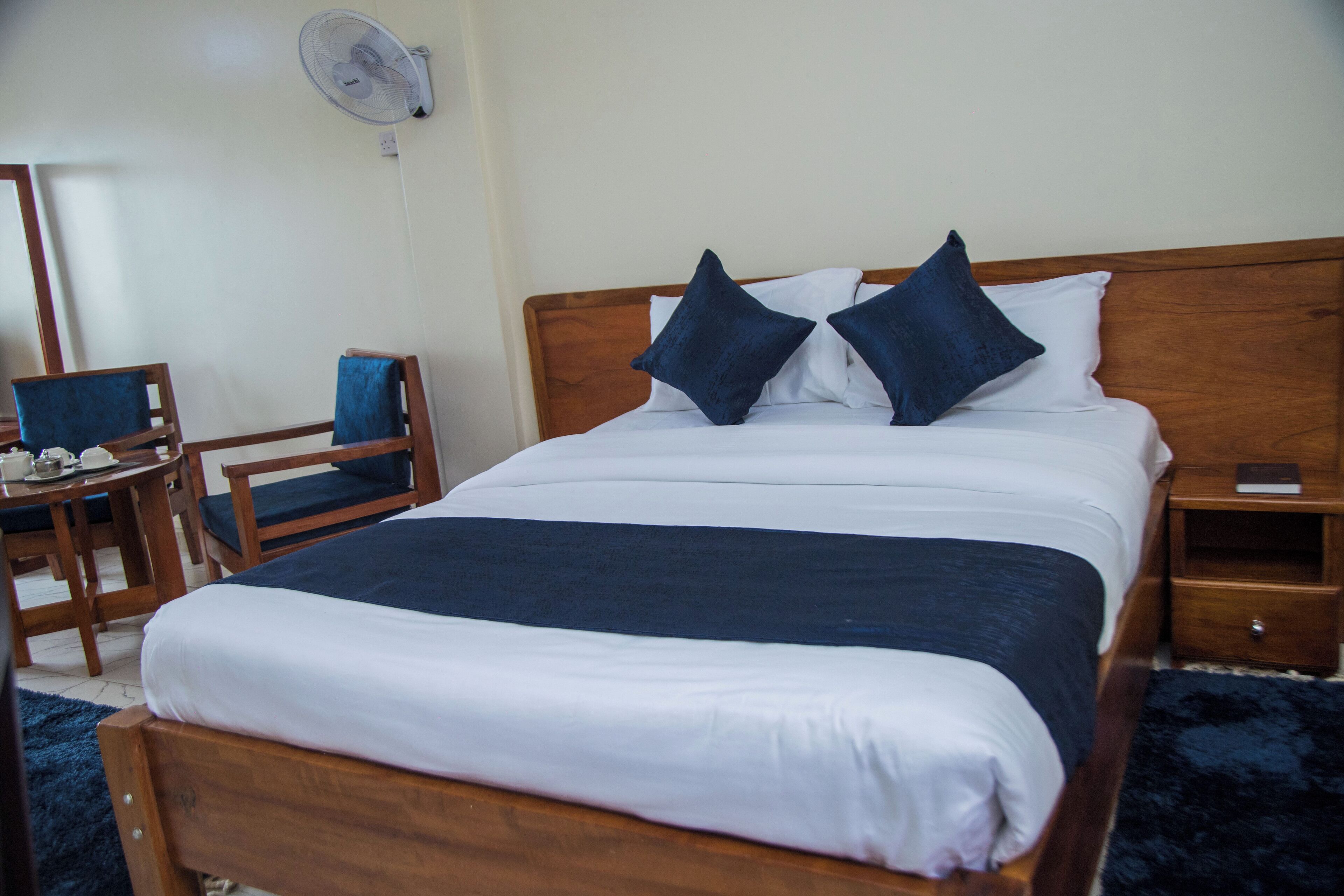 A neatly made bed with a wooden headboard, two pillows, and a bedside table with a lamp.