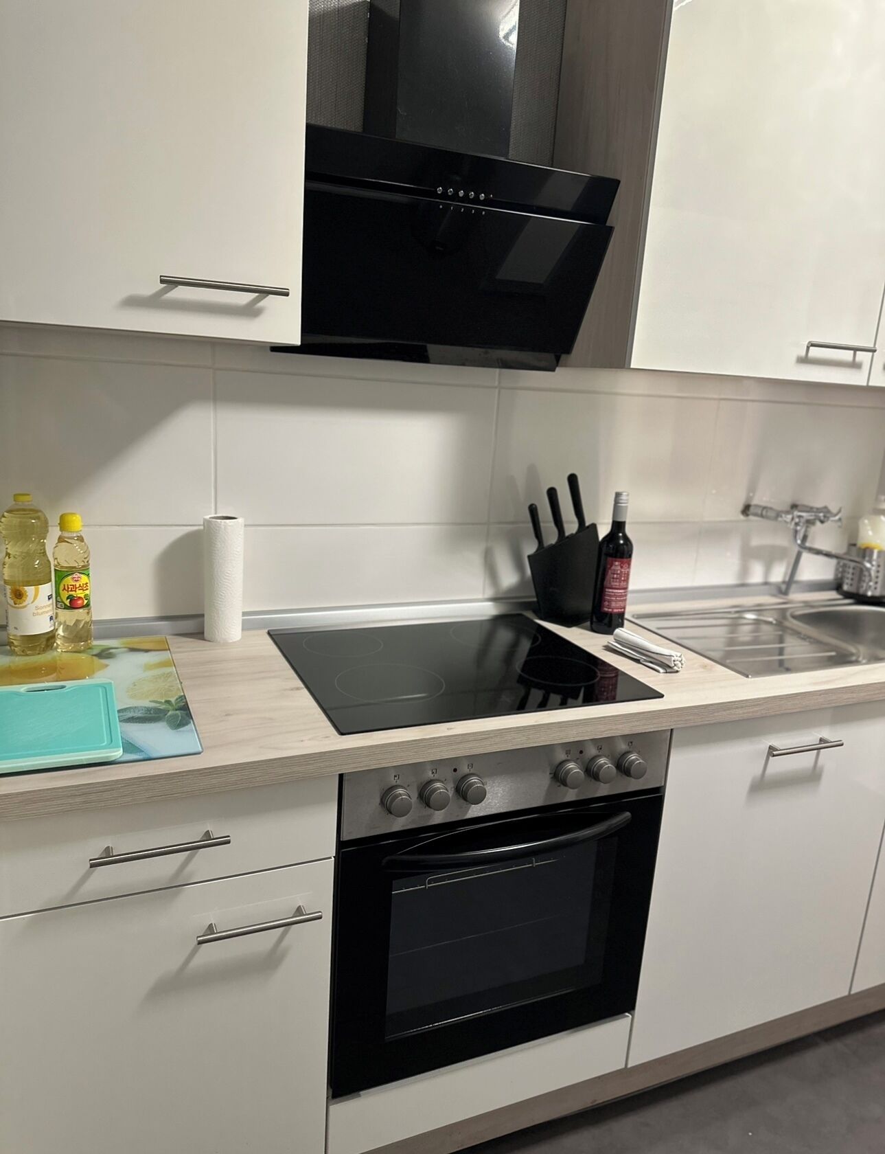 A modern kitchen with white cabinetry, a black stove, and a built-in oven.