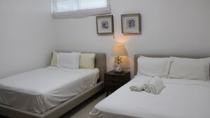 A hotel room with two single beds, a nightstand with a lamp, and two framed pictures on the wall. - Las Olas 2BR 6PAX 3Bds HugeTerrace (Guayacanes)