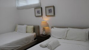 A hotel room with two beds, a nightstand with a lamp, and two framed pictures on the wall. - Las Olas 2BR 6PAX 3Bds HugeTerrace (Guayacanes)