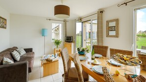 A cozy living room with a brown sofa, a wooden coffee table, and a dining table set for a meal.