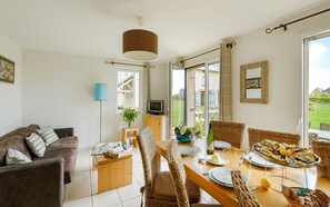 Enjoy a spacious living area with a large window offering a view of the outdoors, a TV, and comfortable seating options.