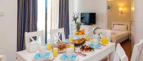 A breakfast setup with a table, chairs, and a TV in the background.