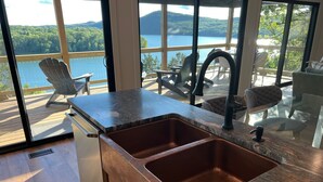 Une cuisine dotée d’une grande fenêtre donnant sur un lac et des montagnes.
