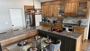 Une cuisine moderne dotée d’un îlot central, de meubles en bois et d’un réfrigérateur en acier inoxydable.