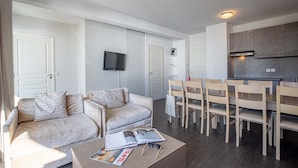 Un saló modern amb un sofà, una taula de centre i una zona de menjador amb cadires i una taula.