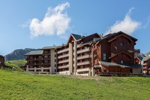 Un immeuble en bois à plusieurs étages, doté de balcons, qui se dresse sur fond de montagnes.