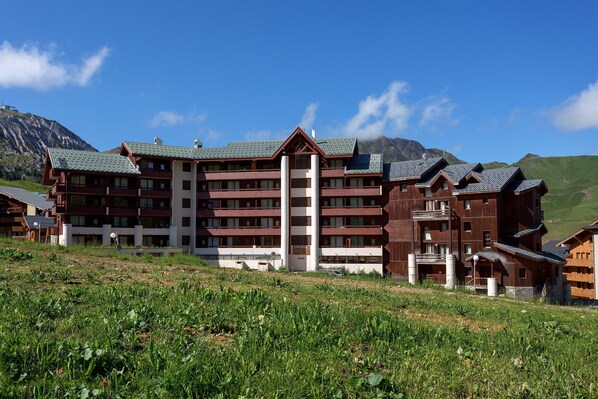 Un hôtel à plusieurs étages doté d’une cour intérieure, entouré d’un paysage montagneux.
