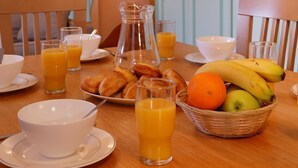 Et morgenbord med tallerkener, glas med appelsinjuice, en skål, en frugtkurv og bagværk.