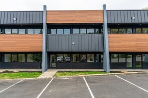 Ein modernes Gebäude mit zwei Ebenen, großen Fenstern und einem Parkplatz davor.