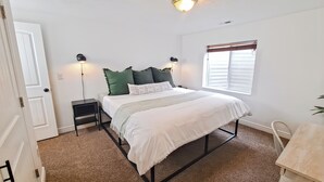 Ein Schlafzimmer mit einem Bett, Nachttischen, einer Fensterbank und einer Deckenleuchte.