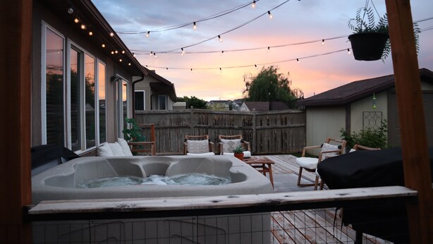 Ein Garten mit Whirlpool, Lichterketten und Gartenmöbeln.