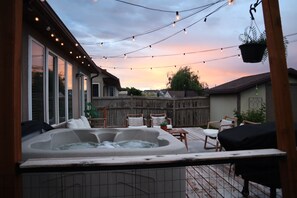 A backyard with a hot tub, string lights, and outdoor furniture.
