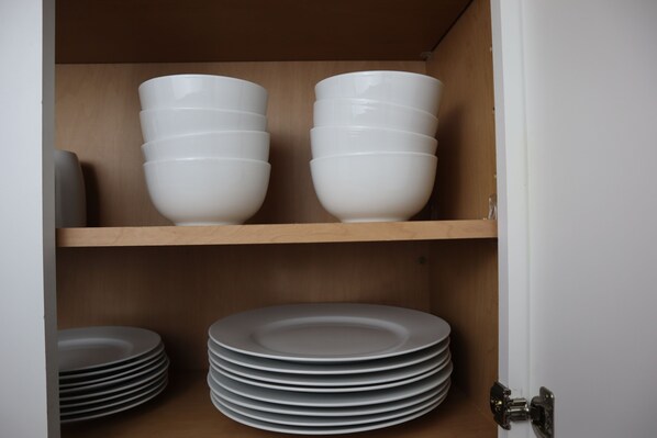 A kitchen cabinet with white bowls and plates.