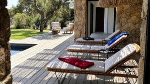 A wooden deck with lounge chairs and a stone wall.