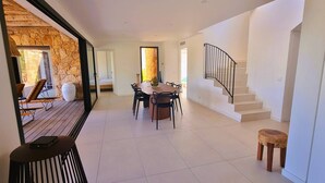 A spacious dining area with a large table and chairs, a staircase, and a view of the outdoors.