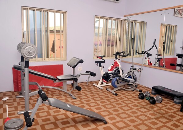 A gym with exercise equipment, a red bench, and a patterned floor. - Coronia Hotel (Lagos)