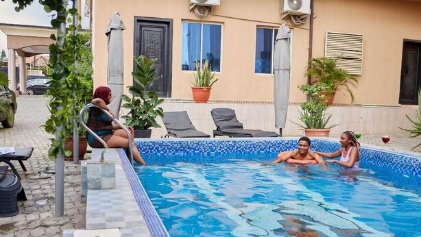 Une piscine dont les bords sont recouverts de carreaux, avec des chaises longues et des plantes en pot.