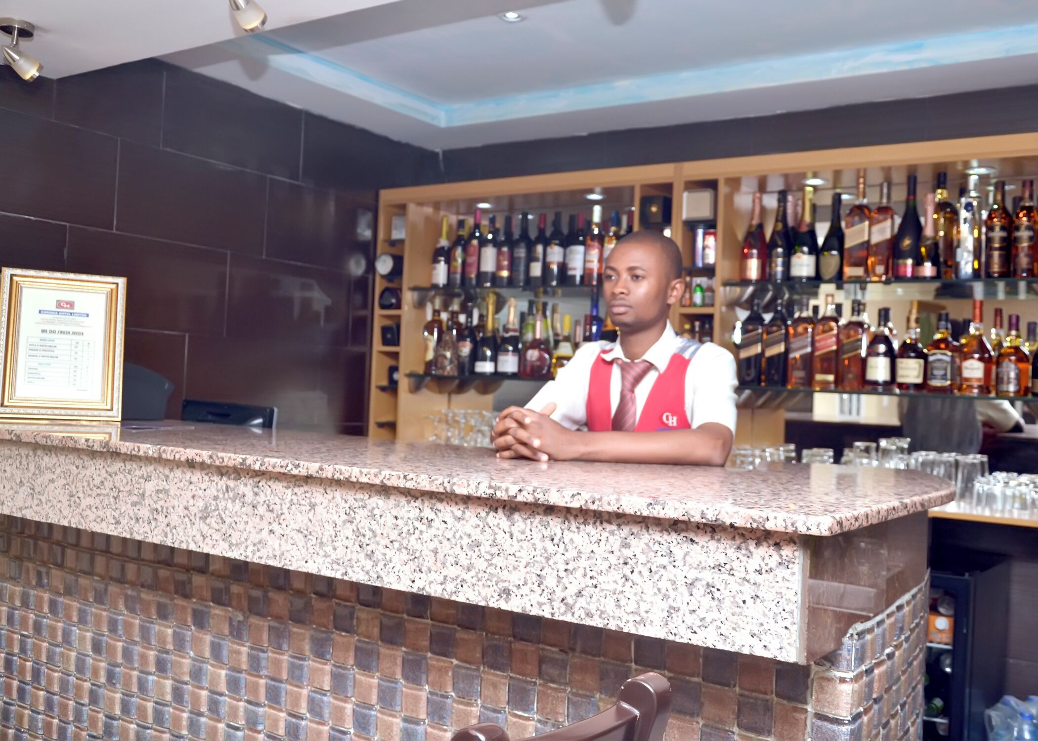 A bar area with a granite countertop and a variety of liquor bottles in the background.